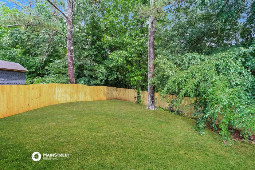 a fenced backyard with trees and a wooden fence