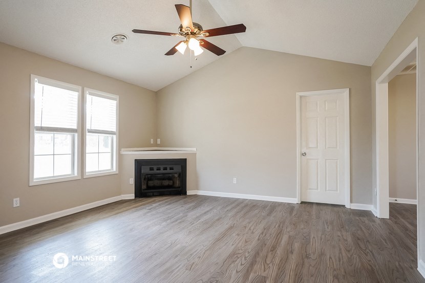 the living room of an empty home with a ceiling fan