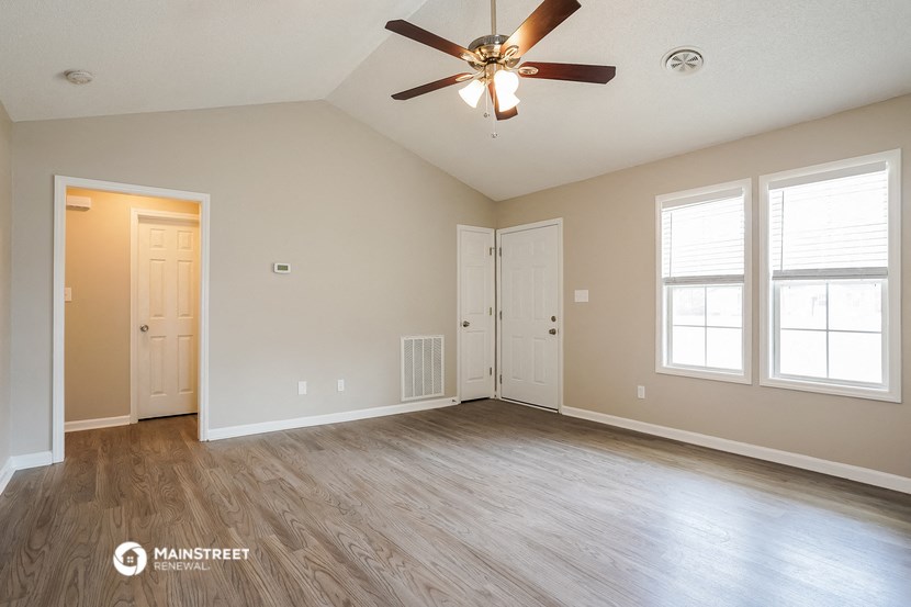 the spacious living room with hardwood floors and a ceiling fan
