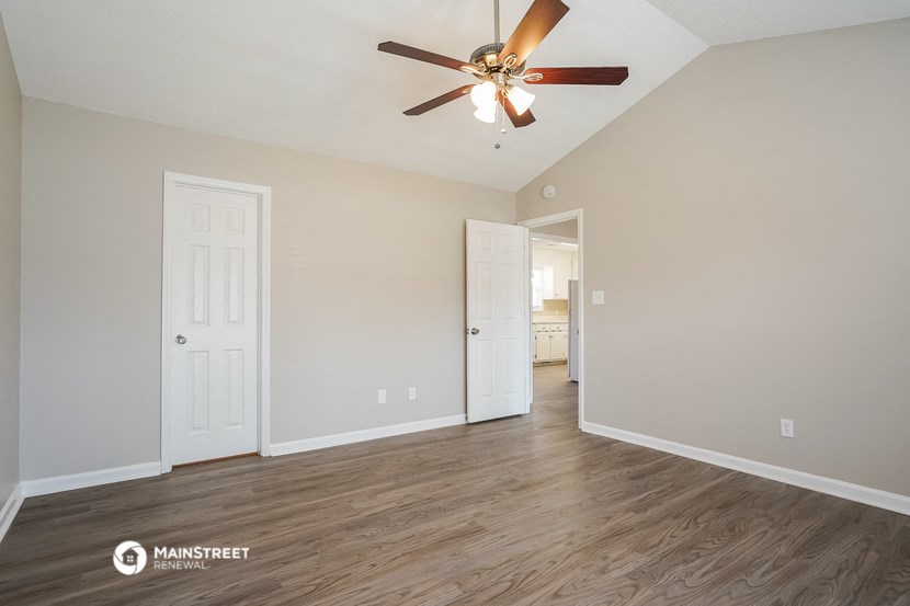 a living room with a ceiling fan and a door to a bathroom