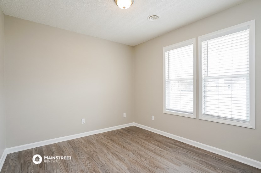 the spacious living room with wood flooring and two windows