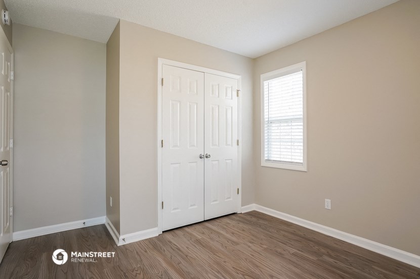 the spacious living room with two closets and a window