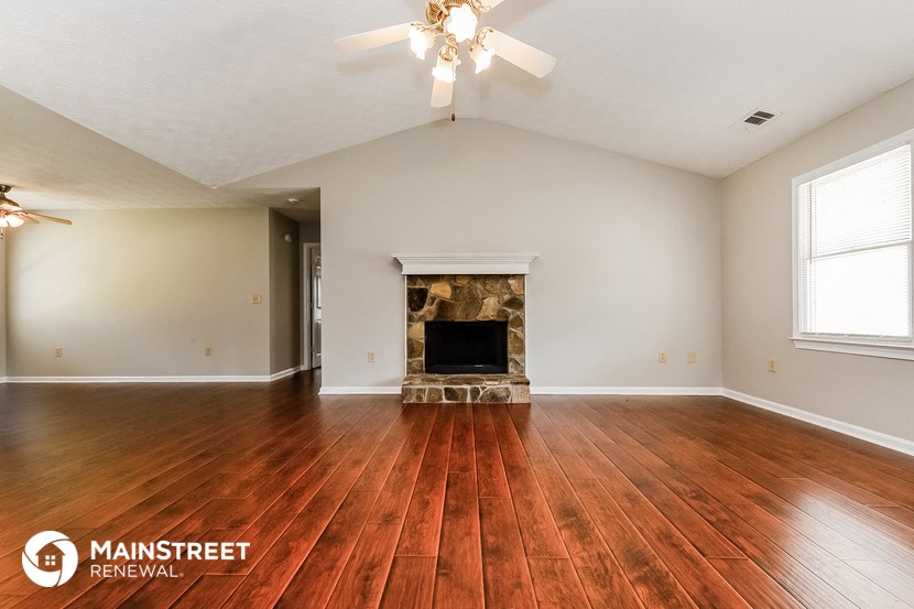 the living room with wood floors and a fireplace