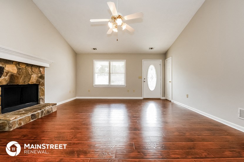 an empty living room with a fireplace and a ceiling fan
