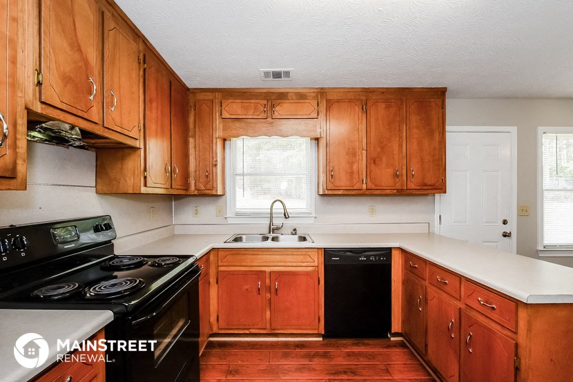 a kitchen with wooden cabinets and black appliances and white counter tops