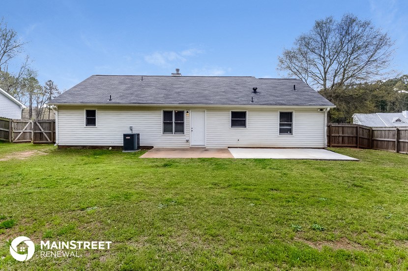 a small white house with a grassy yard and a wooden fence