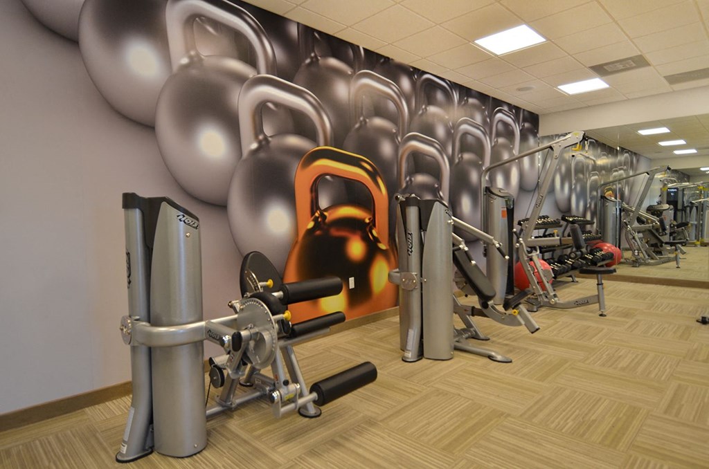 a row of exercise equipment in a gym with a wall of balloons