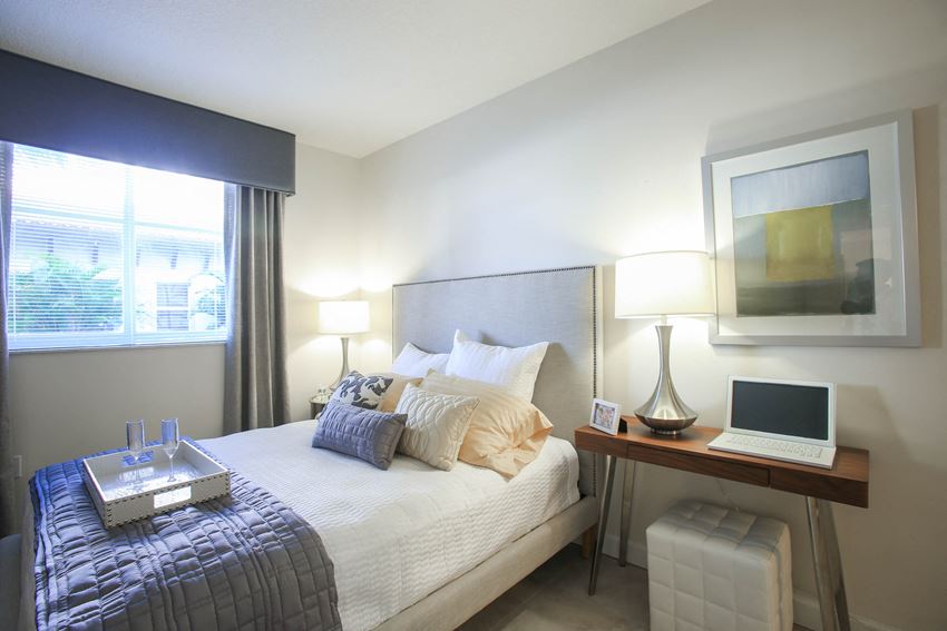 a bedroom with a bed and a laptop on a desk