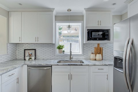a white kitchen with white cabinets and a sink