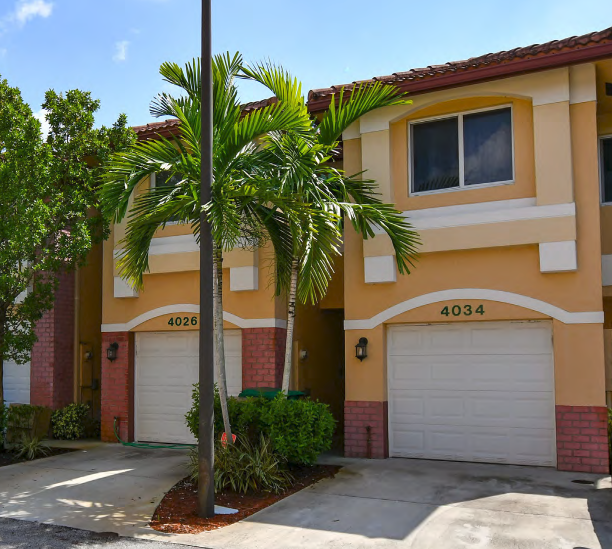 a palm tree in front of a house with two garage doors