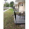 A black metal fence with a gate is in front of a house.