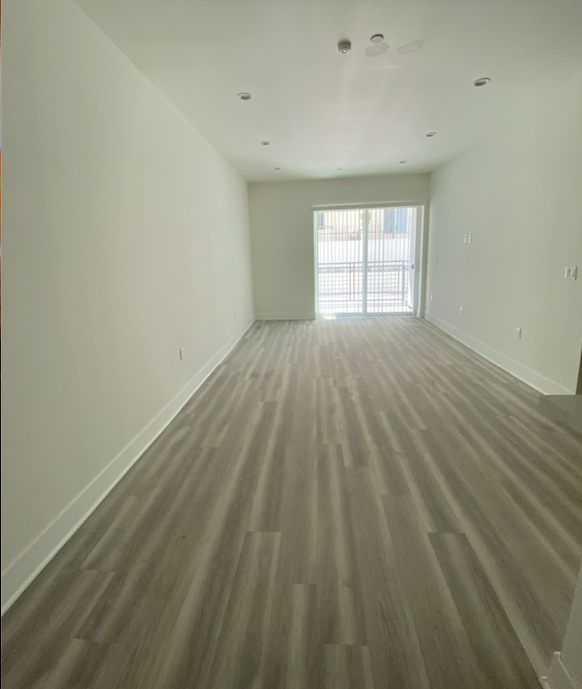 an empty living room with wooden floors and a window