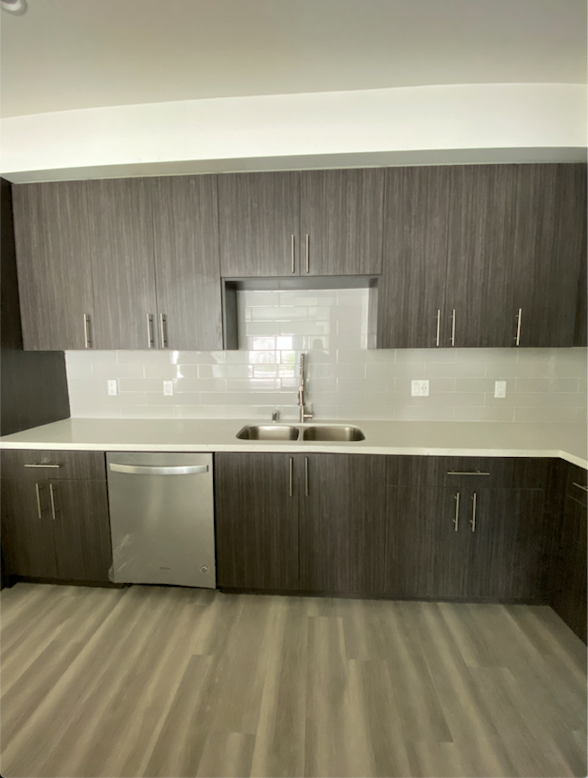 an empty kitchen with white counter tops and wooden cabinets