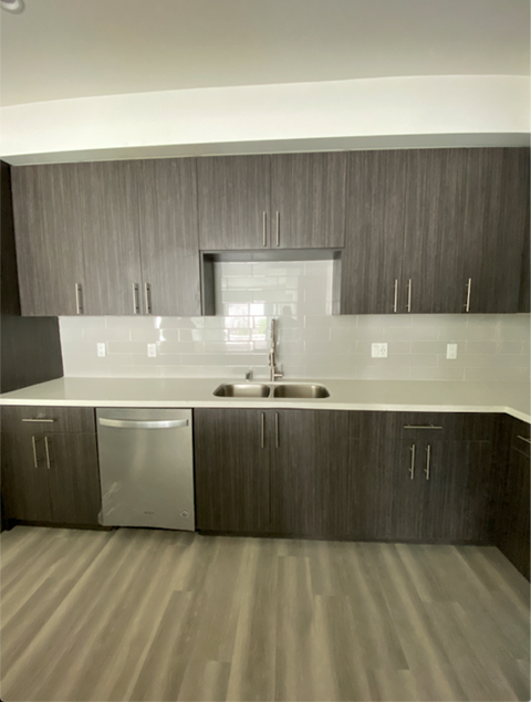 an empty kitchen with white counter tops and wooden cabinets