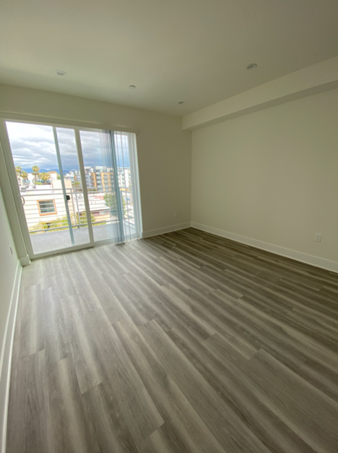 an empty living room with wooden floors and a sliding glass door