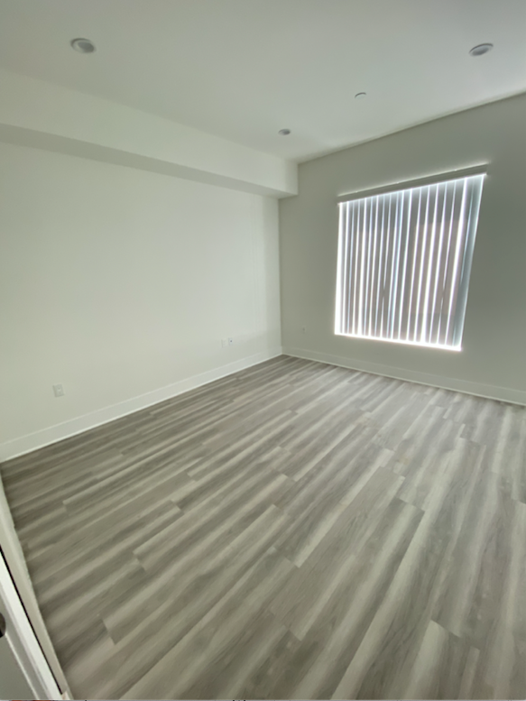 an empty room with wooden floors and a window