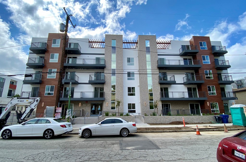 an apartment building with two cars parked in front of it