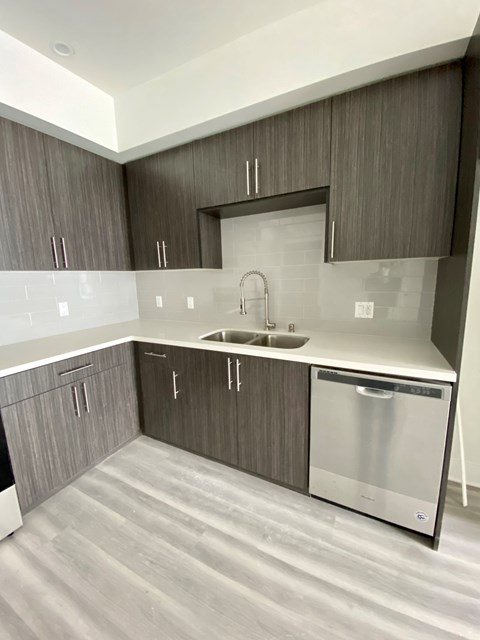 an empty kitchen with wooden cabinets and a stainless steel dishwasher