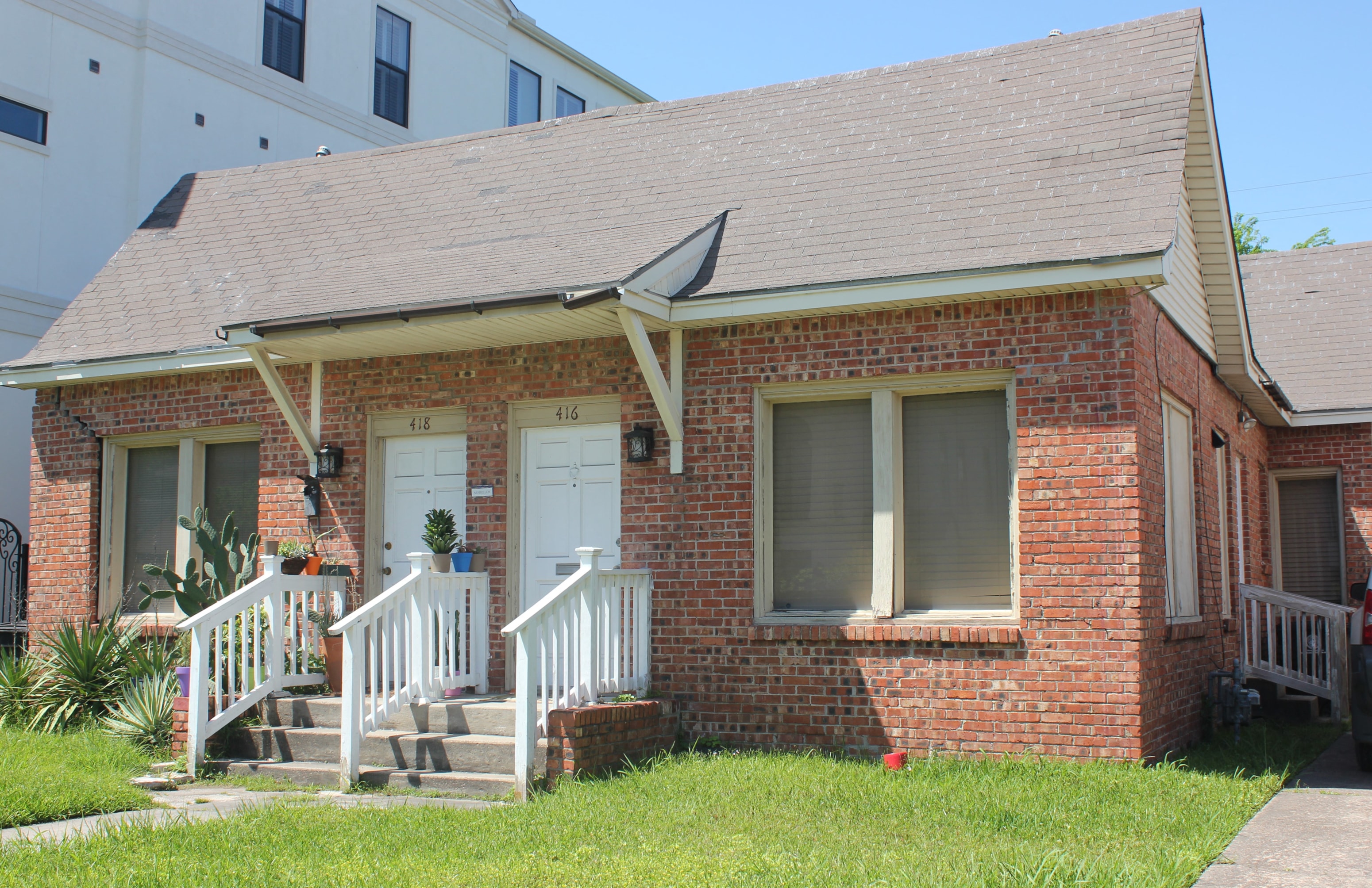 A small red brick house with a white door and windows.