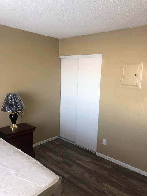 a bedroom with a white closet and a lamp on a table