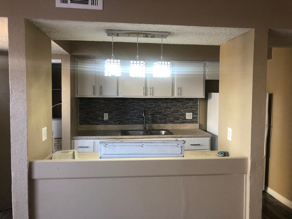 an empty kitchen with white cabinets and a counter top