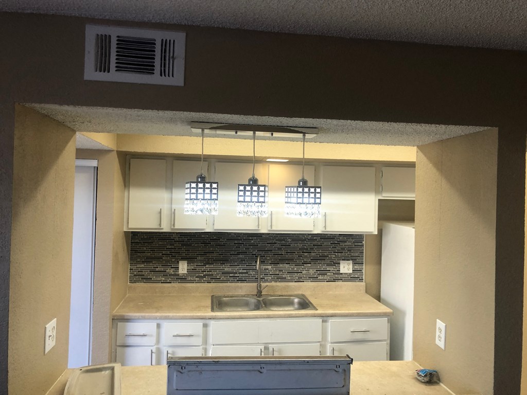 an empty kitchen with white cabinets and a sink