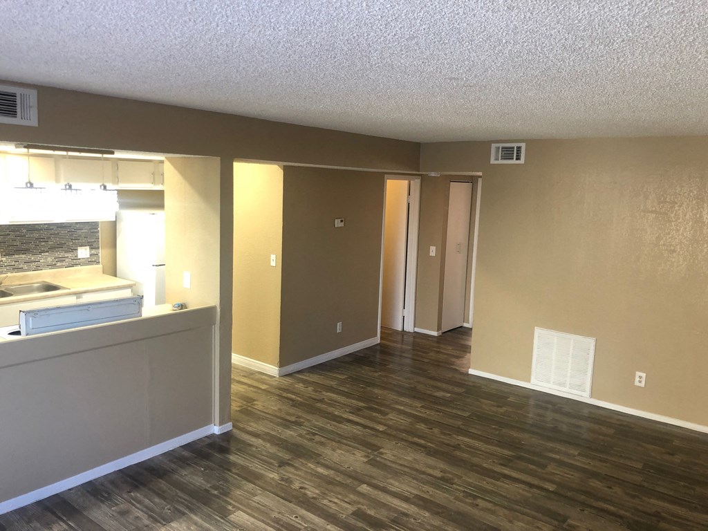 an empty living room and kitchen with wood flooring