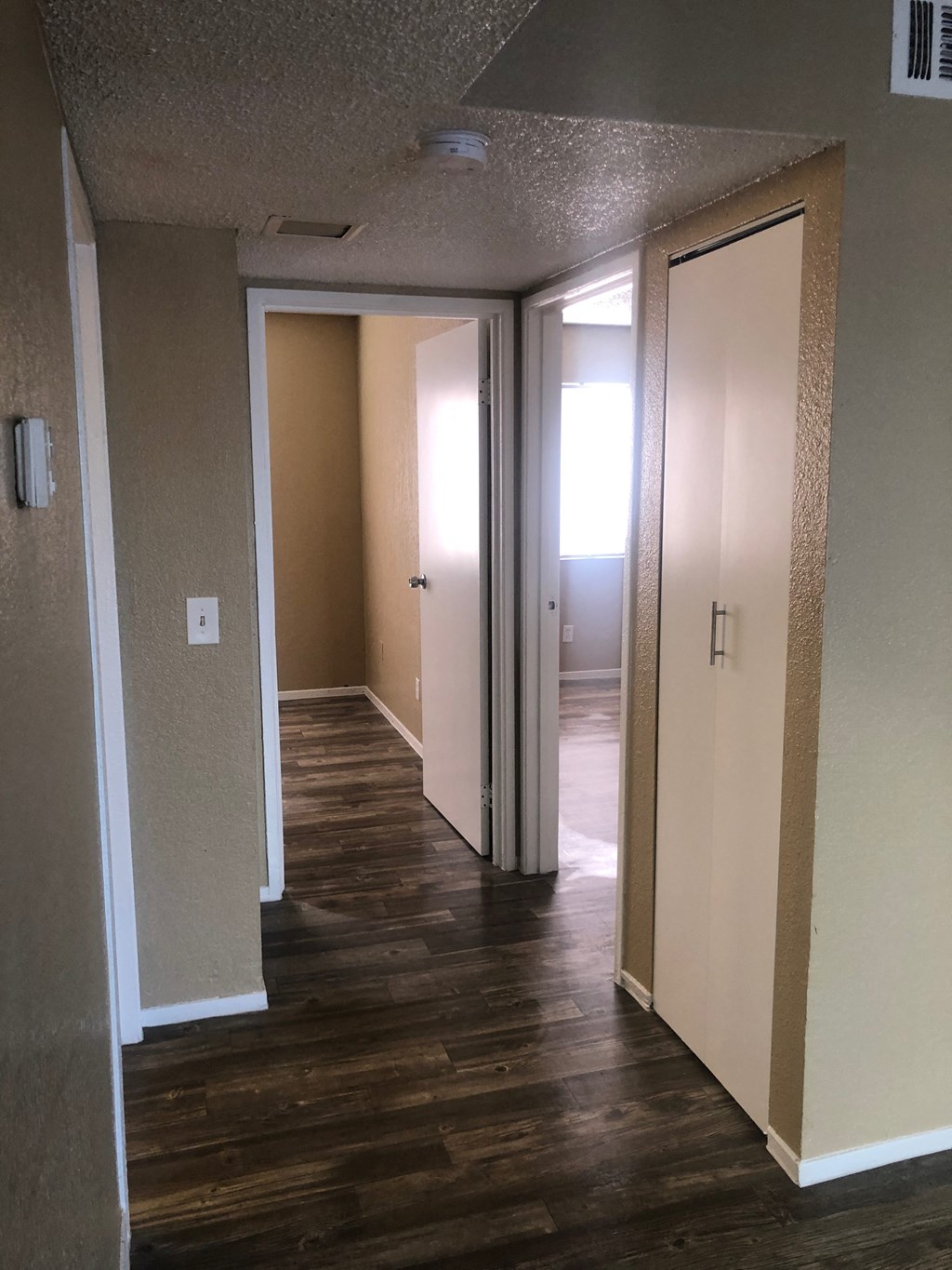 a living room with wood floors and a hallway with three doors