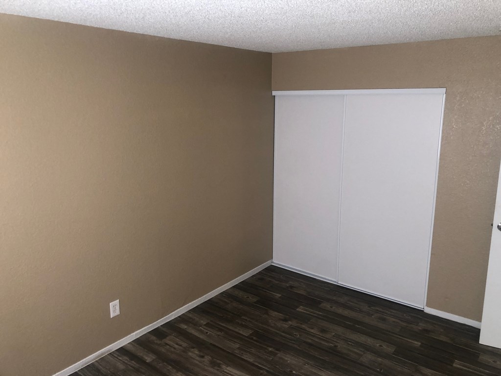 an empty room with a wood floor and a white closet