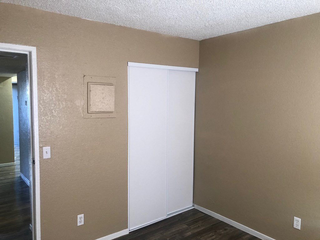 an empty room with a white door and a hallway to a closet