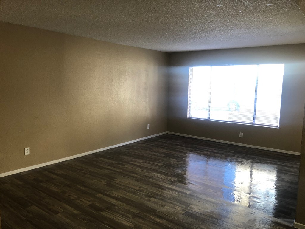 an empty living room with wood floors and a window