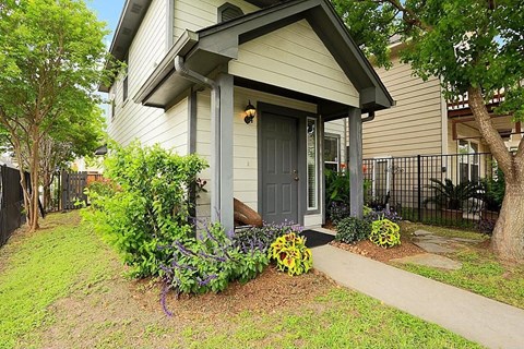 the front door of a house with plants and a sidewalk