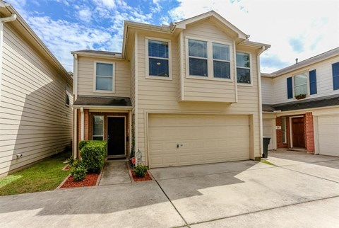 A two-story house with a garage and a driveway.