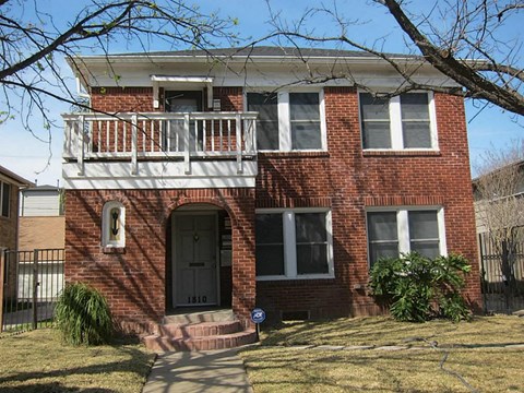 a brick house with a balcony and a black door