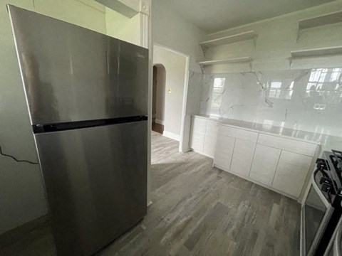 A modern kitchen with a stainless steel refrigerator and wooden flooring.