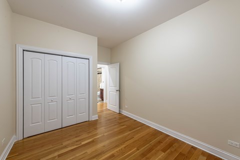 A room with a white door and wooden flooring.