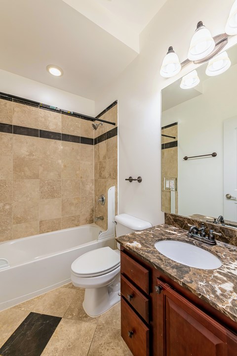 A bathroom with a beige tiled shower and a white toilet.