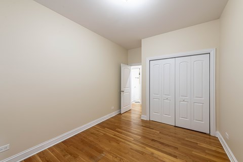 A room with a white door and wooden flooring.