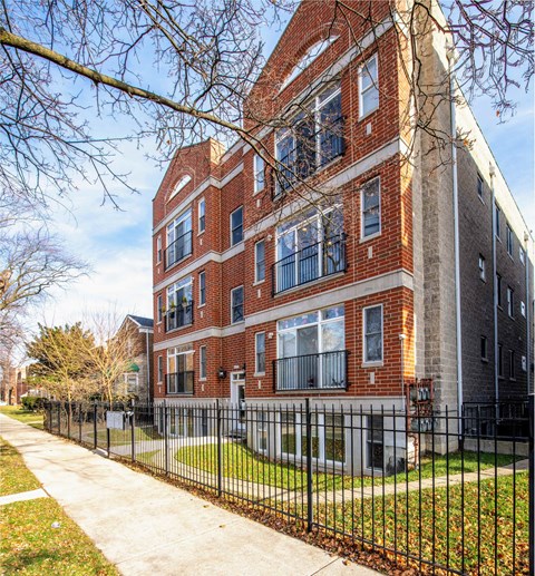 A red brick building with a black fence in front.