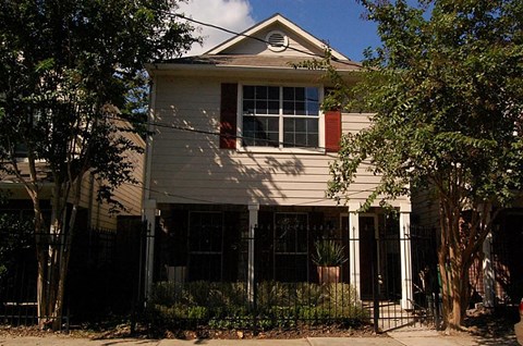 A house with a red window trim and a black gate.