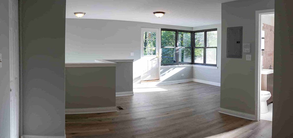 an empty living room with hard wood floors and a window