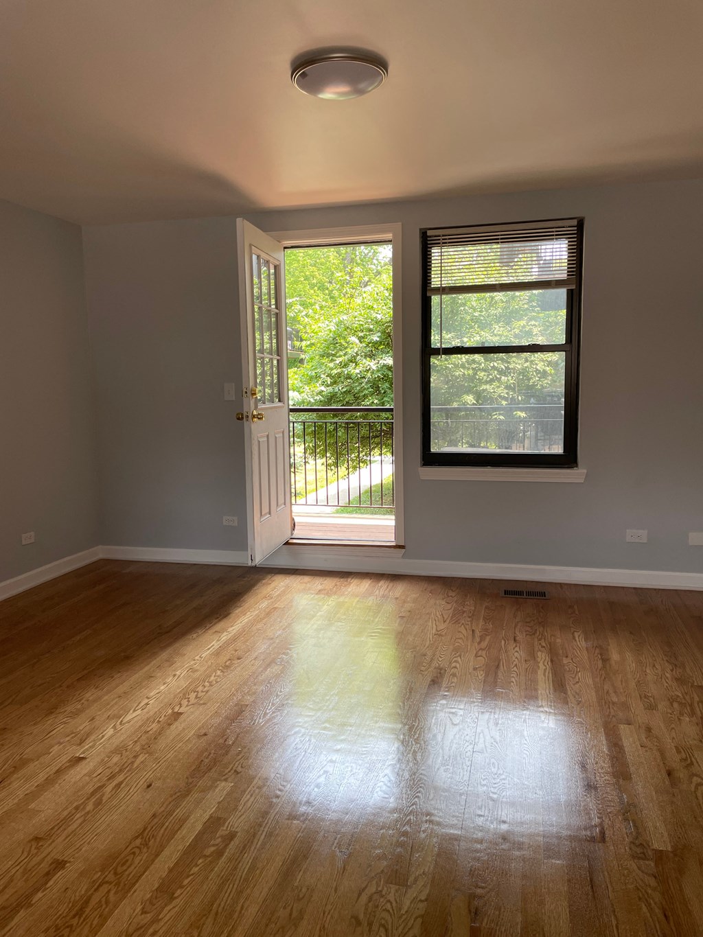 an empty living room with wood floors and a window