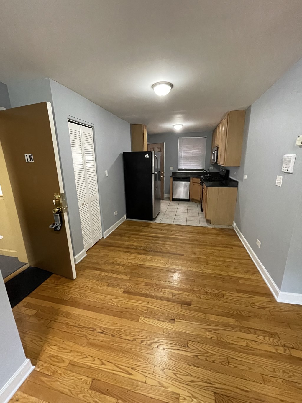 a kitchen and a hallway with wood floors and a refrigerator and