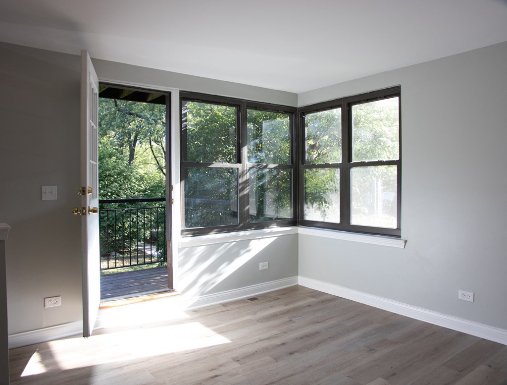 an empty living room with large windows and a door to a balcony