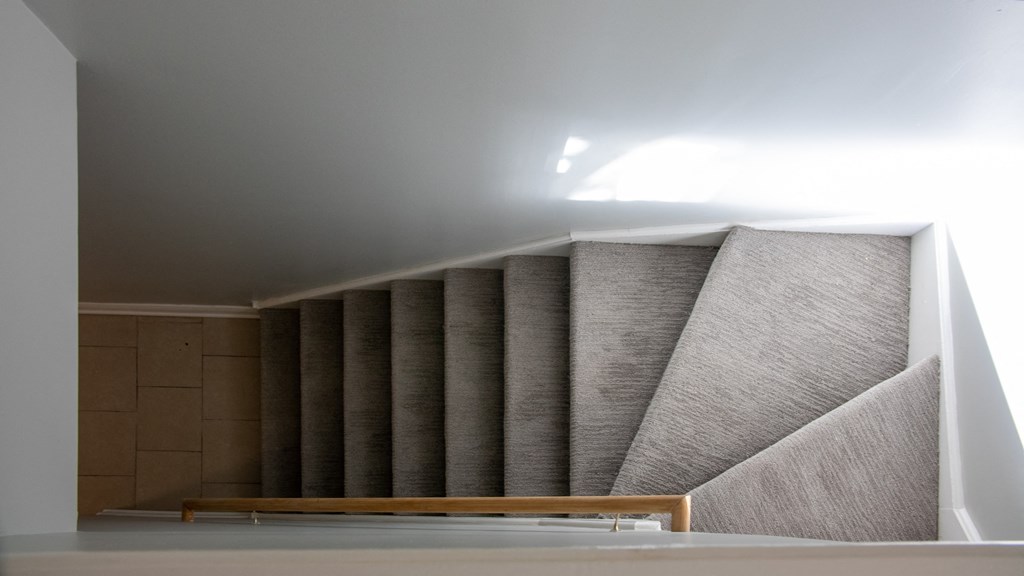 a view of the top of a staircase with grey walls and a wooden floor