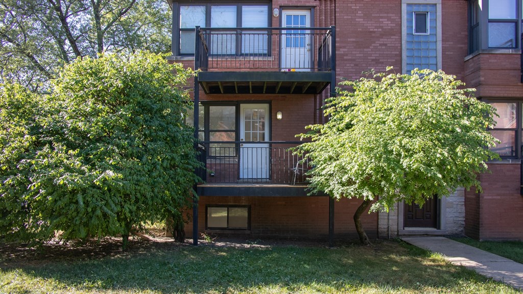 the front of a brick apartment building with two trees