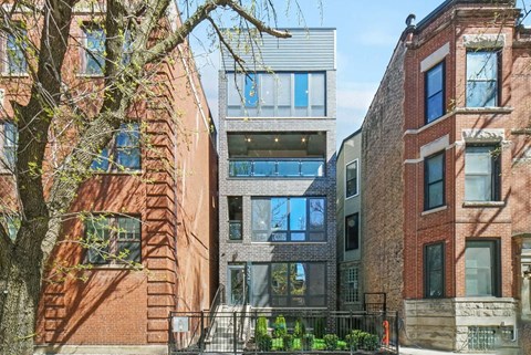 A modern building with glass windows is situated between two older brick buildings.
