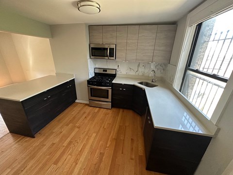 an empty kitchen with wooden floors and black cabinets