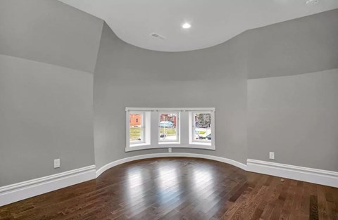 A room with a wooden floor and a large window with pictures on it.