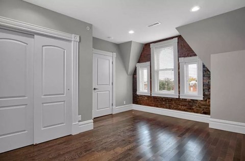A room with a brick wall and wooden floors.